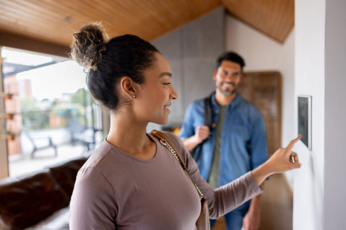 Couple leaving their house and setting the alarm using a home automated system