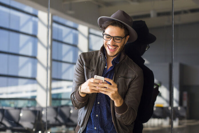 Young,Traveler,On,An,Airport,,With,A,Leather,Jacket,Texting
